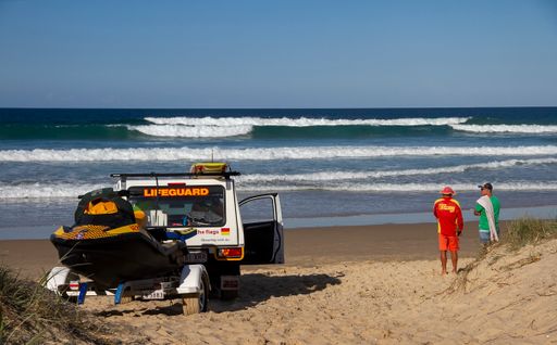 Surf lifesaver advising swimmer in rough waves Marcoola Beach Sunshine Coast Australia