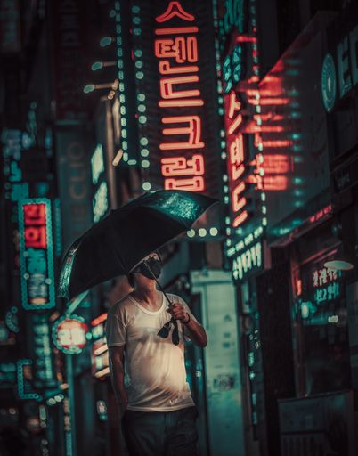 An adult person holding an umbrella and walking down the streets of Busan on a rainy night in South Korea