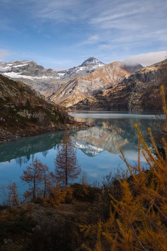 Autumn landscape view of a mountain reflecting in a turquoise lake with golden larches in the foreground