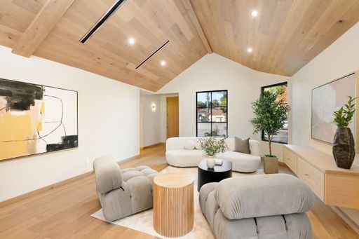 Modern living room with elegant decor, featuring plush chairs, abstract art, and large windows, creating a cozy yet stylish atmosphere.
