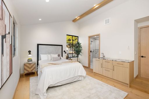Modern bedroom interior with wooden floors, a cozy bed, and stylish decor in a bright and airy space.