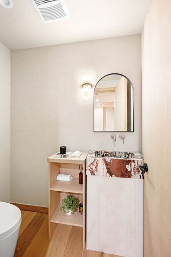 Modern bathroom with marble sink, wooden shelves, and minimalist decor, featuring a sleek mirror and soft lighting.