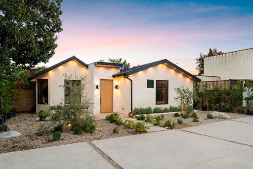 Modern single-story house with landscaped front yard at sunset.