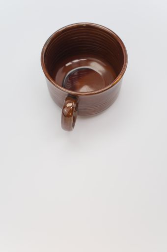 A vertical shot of a brown mug isolated on a white background
