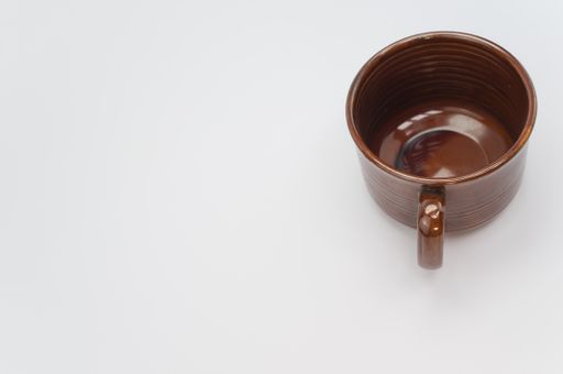 A high angle shot of a brown mug isolated on a white background