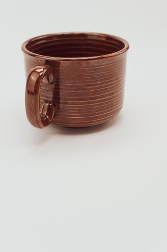 A vertical shot of a brown mug isolated on a white background