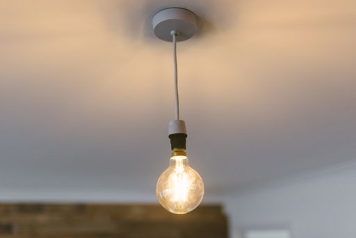 A closeup shot of a large illuminated light bulb hanging from the ceiling