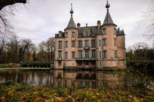 Poeke Flanders Belgium 11 26 2024 A picturesque castle with turrets reflected in a calm moat, surrounded by autumn trees.
