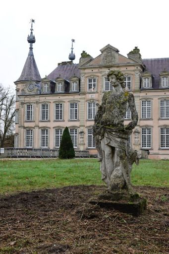 Poeke Flanders Belgium  A grand historic chateau with ornate architecture and a statue in the foreground, surrounded by a grassy field and trees.