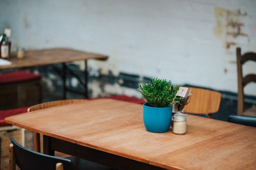 A closeup shot of a blue pot with a green plant and a jar of salt next to it at a cafe