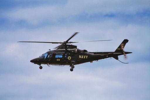 A low angle shot of a military helicopter with "Navy" text on board in flight in Australia