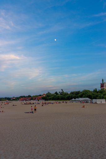 A vertical shot of people on a sandy beach under the sunlight in Sopot, Poland