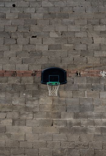 A vertical shot of a portable basketball hoop attached to a brick and block wall