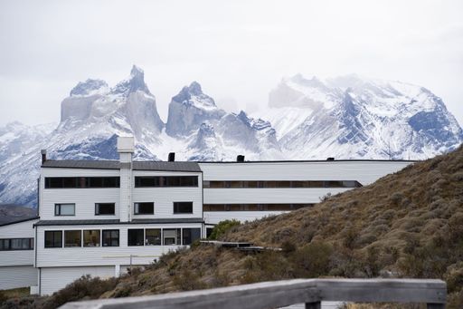 Modern building in front of snow-capped mountains in Torres del Paine, Chile, showcasing stunning architecture and natural beauty.