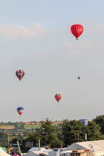 A vertical shot of multiple hot air balloons flying in the sky at the Bristol Balloon Festival