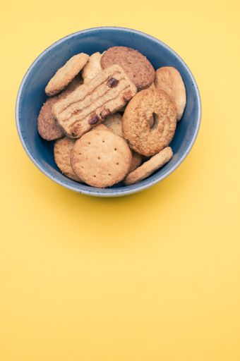 A vertical closeup of a bowl of cookies on the yellow background.