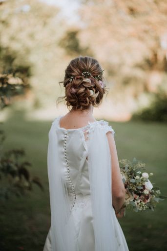 A vertical shot of a bride with a bridal hairstyle wearing wedding dress holding a flower bouquet
