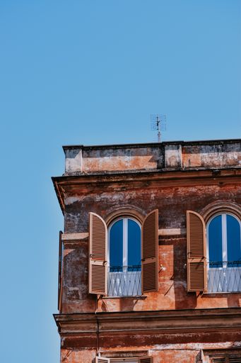 A vertical shot of arched windows with wooden shutters of an old residential building in Rome