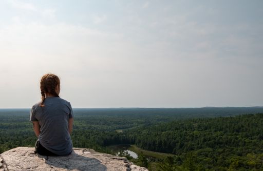 A caucasian female sitting at top of The Crack hiking trail in Killarney provincial park, Sudbay, Canada
