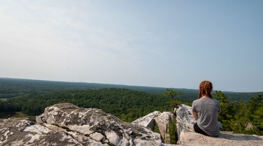 A caucasian female sitting at top of The Crack hiking trail in Killarney provincial park, Sudbay, Canada