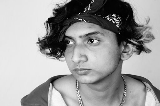 A grayscale shot of a serious South Asian guy from India with long ombre hair wearing a bandana