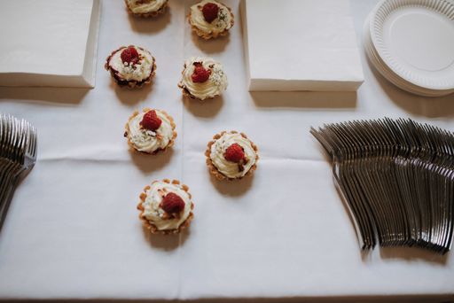 An overhead shot of cupcakes and dishware on a white surface