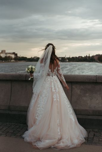 A vertical full body shot of a bride wearing  white gown and wedding dress standing on a bridge