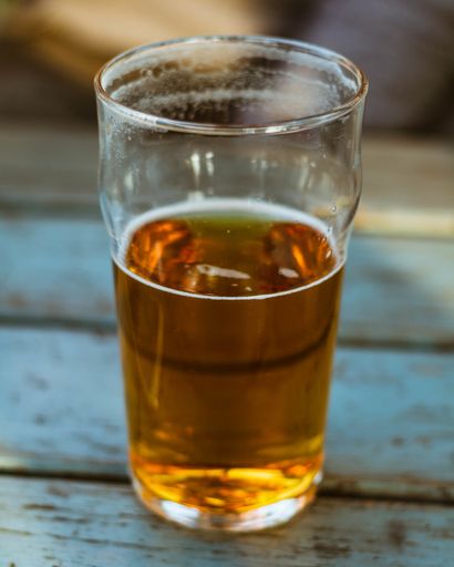 A vertical closeup shot of a glass of beer on a wooden surface