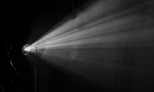 A projector beam casting light through smoke in a dark room, creating a dramatic visual effect.