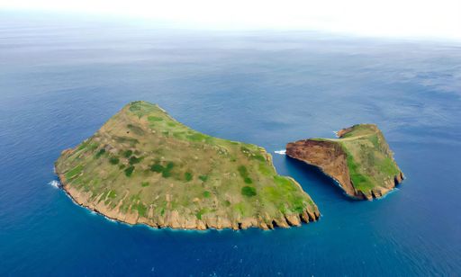 Aerial view of the green and rugged islet of Vila Franca do Campo in the Azores, surrounded by deep blue ocean waters.