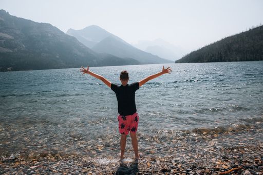 A closeup of a man standing on the shore with stretched hands.