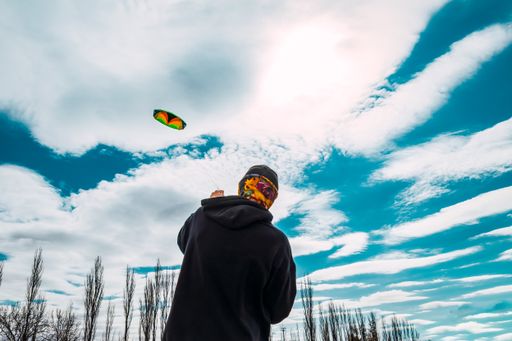 A closeup shot of a boy flying a big kite on a windy day
