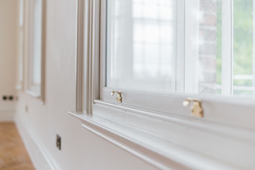 A closeup shot of a gold sash lock on a white window