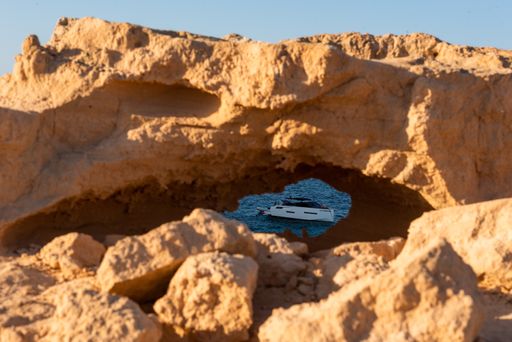 A boat seen through the hole of a rocky cliff in Formentera island, Spain