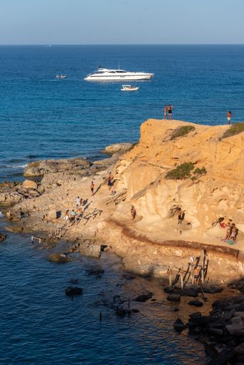 A vertical shot of a rocky beach of Formentera island with many tourists