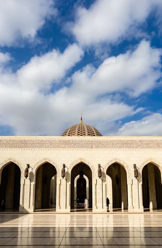 A majestic mosque with a grand dome and a row of arched entrances. The beautiful architecture is reflected in the shiny floor
