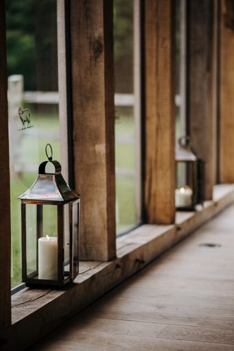 A vertical shot of a lantern with a white candle in it on a wooden surface