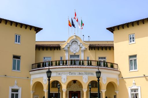 The elegant facade of the Country Club Lima Hotel with flags under a clear blue sky in Lima, Peru