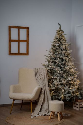 A cozy living room with a decorated Christmas tree, armchair, and blanket