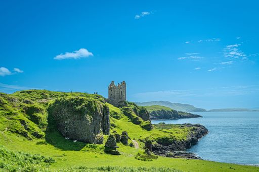 A scenic view of the ruins of Gylen Castle by the sea on a sunny day in Scotland