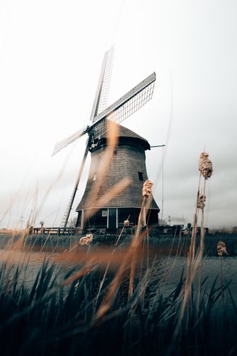 A beautiful vertical shot of a spinning windmill with clear white sky in Rustenburg, North Holland