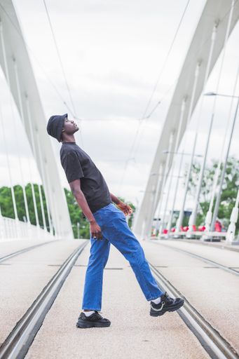 A vertical shot of a young afro-American man posing outside in France