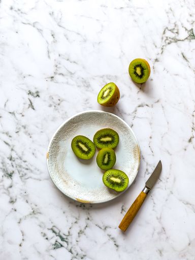 Sliced Kiwifruit on white ceramic plate with knife