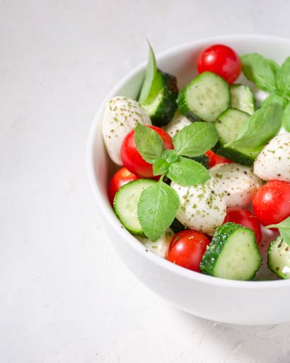 half bowl of salad with mozzarella cheese, cucumber, and cherry tomatoes.