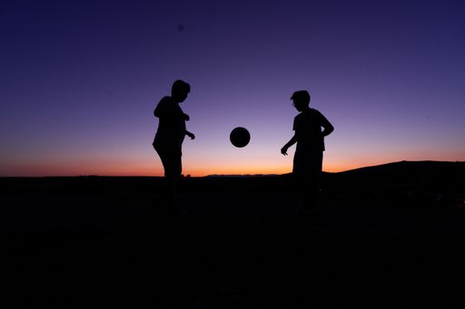A beautiful shot of the silhouettes of two children playing ball during sunset