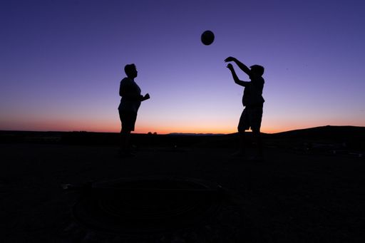 A beautiful shot of the silhouettes of two children playing ball during sunset