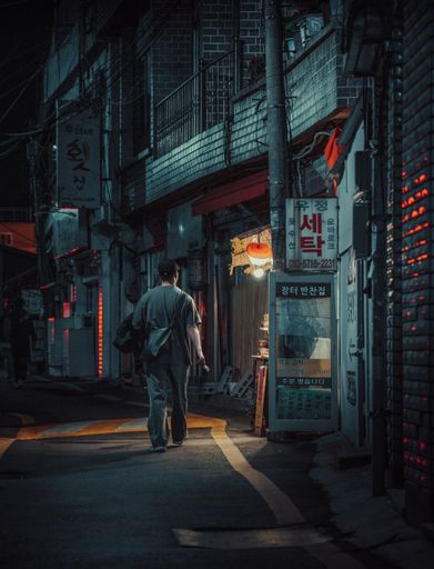 A middle-aged woman walking on the South Korean city street at night