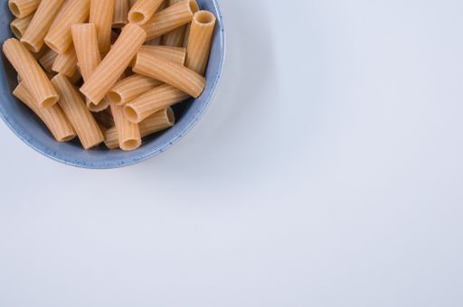 A top view of uncooked rigatoni pasta on a bowl isolated on yellow background