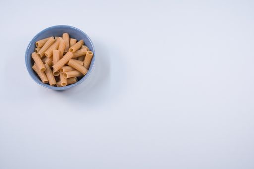 A top view of uncooked rigatoni pasta on a bowl isolated on white background