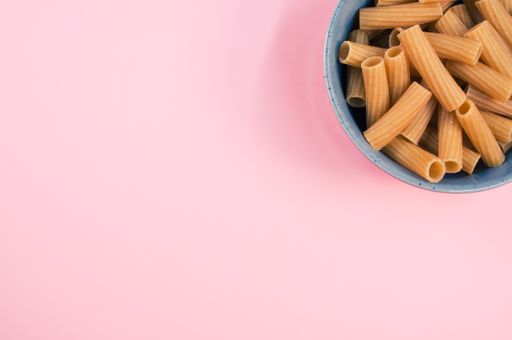 A top view of rigatoni pasta on a bowl isolated on pink background